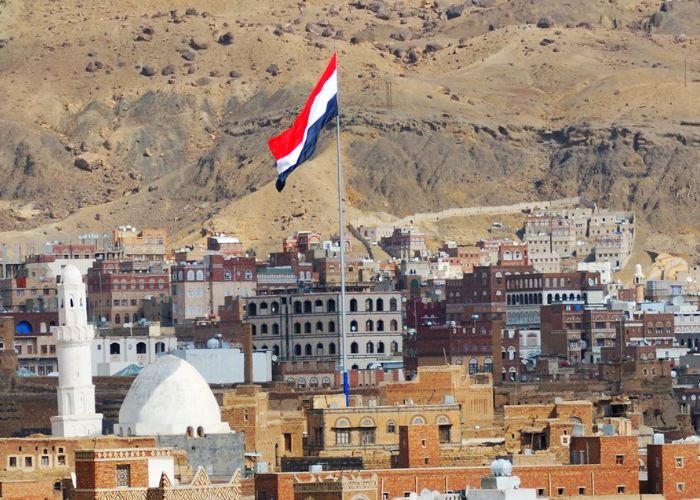 Bandeira do Iêmen no alto da cidade de Sanaa, patrimônio mundial da UNESCO, agora destruída pela guerra civil (Foto: Canva Pro)